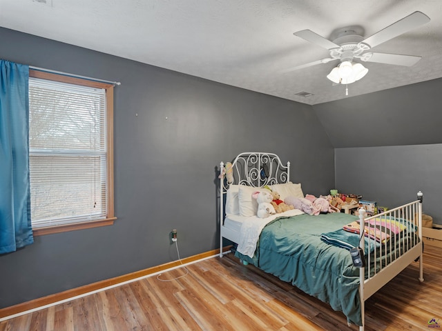 bedroom with ceiling fan, lofted ceiling, hardwood / wood-style floors, and a textured ceiling