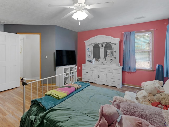 bedroom with a textured ceiling, ceiling fan, and light wood-type flooring