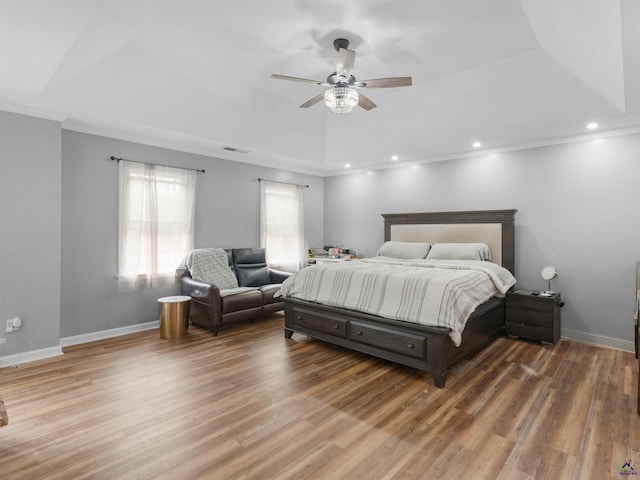 bedroom with hardwood / wood-style flooring, ceiling fan, ornamental molding, and a raised ceiling