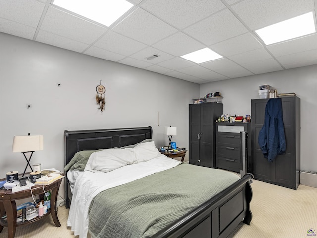 bedroom with a paneled ceiling and light carpet