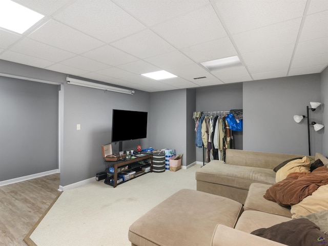 living room with a paneled ceiling and light carpet