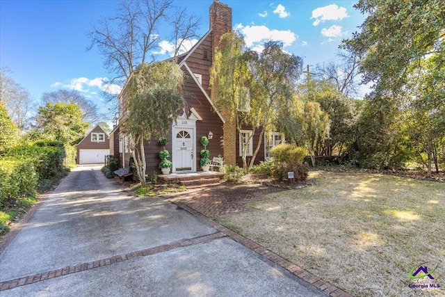 view of front of house featuring a garage, an outdoor structure, and a front yard