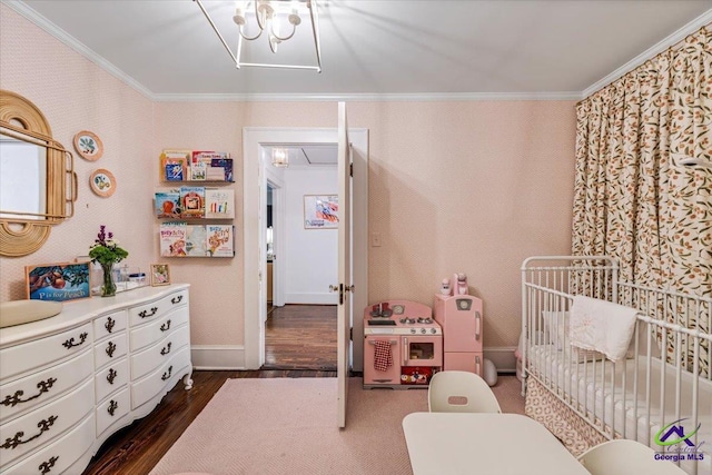 bedroom with crown molding, a nursery area, and dark wood-type flooring