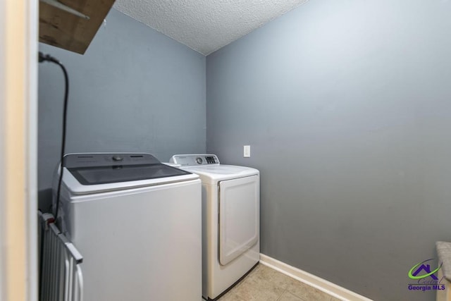 laundry room with washing machine and dryer, a textured ceiling, and light tile patterned floors