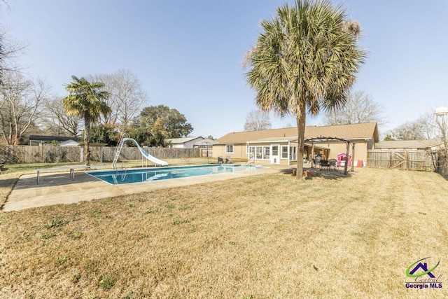 view of swimming pool with a yard, a patio area, and a water slide