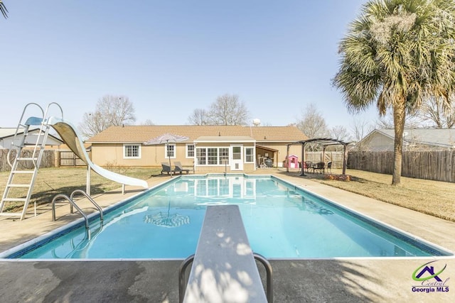 view of swimming pool with a lawn, a water slide, a pergola, a diving board, and a patio area