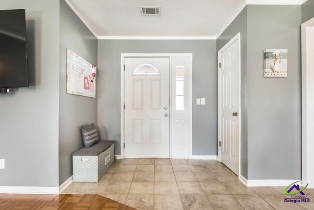 foyer entrance with ornamental molding and light parquet flooring