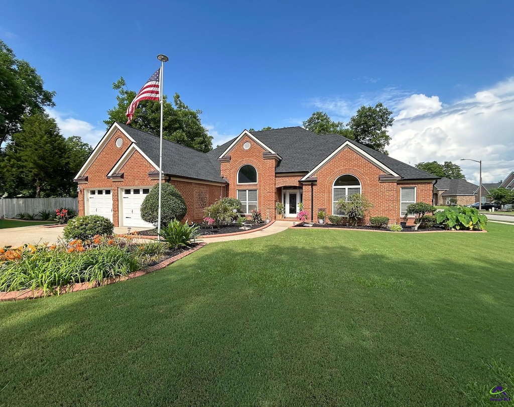 view of front of home featuring an attached garage, brick siding, a front yard, and fence