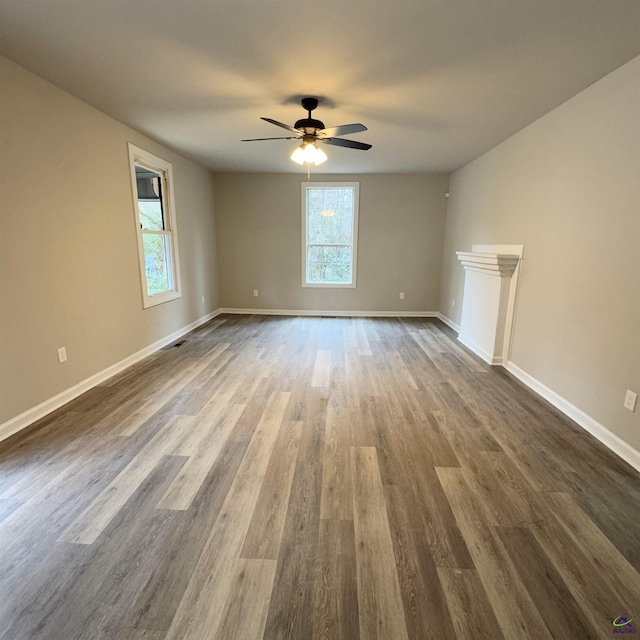 unfurnished living room with dark hardwood / wood-style flooring and ceiling fan