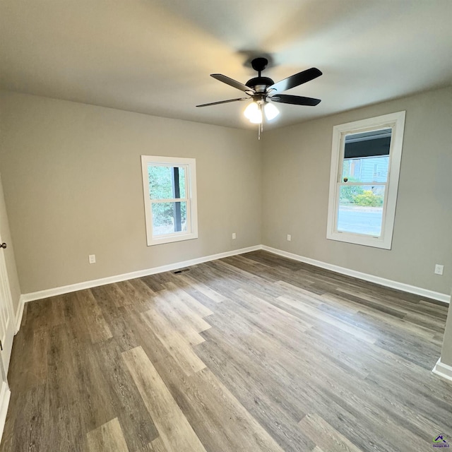 spare room with a wealth of natural light, ceiling fan, and hardwood / wood-style flooring