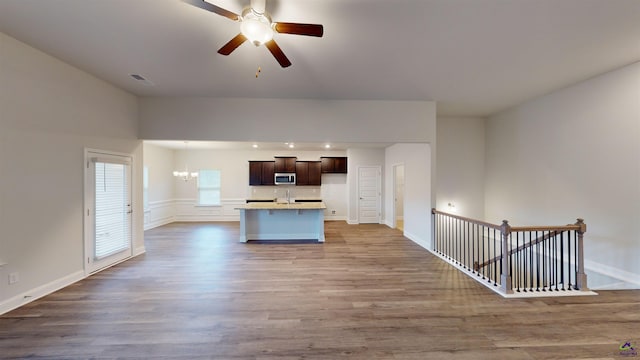 kitchen with ceiling fan with notable chandelier, a kitchen island, dark brown cabinets, and wood-type flooring