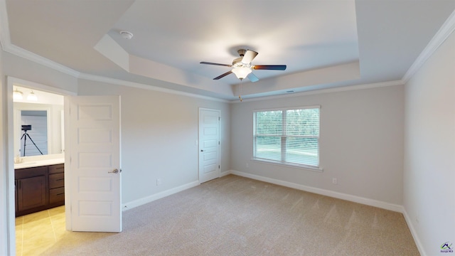 unfurnished bedroom featuring a raised ceiling, a closet, crown molding, and light colored carpet