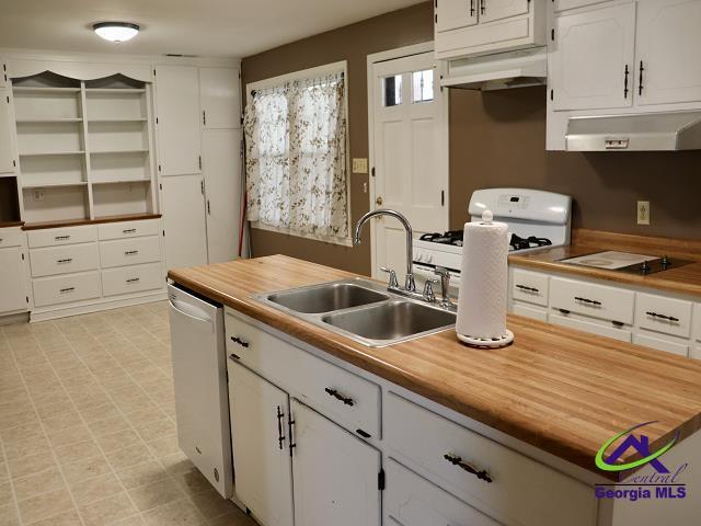 kitchen featuring under cabinet range hood, white appliances, a sink, white cabinets, and light floors