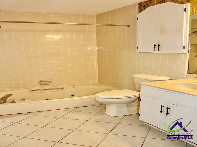 bathroom with toilet,  shower combination, tile patterned flooring, vanity, and tile walls