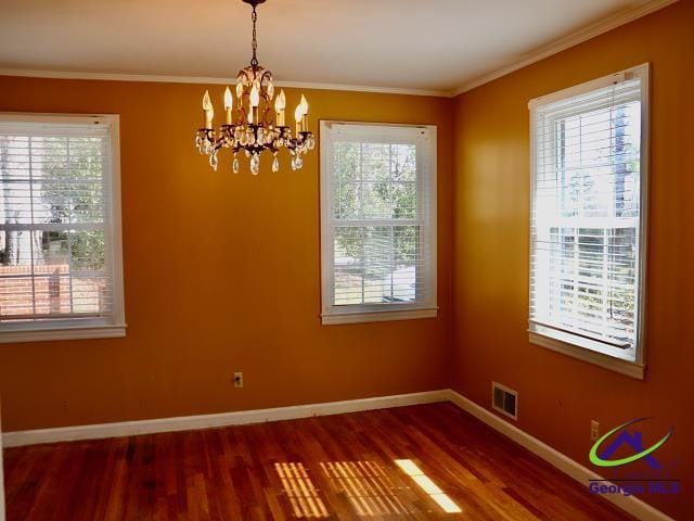 unfurnished dining area featuring ornamental molding, wood finished floors, visible vents, and baseboards