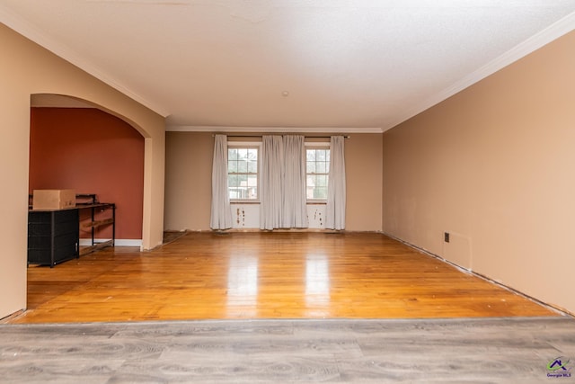 unfurnished room featuring crown molding, arched walkways, and wood finished floors