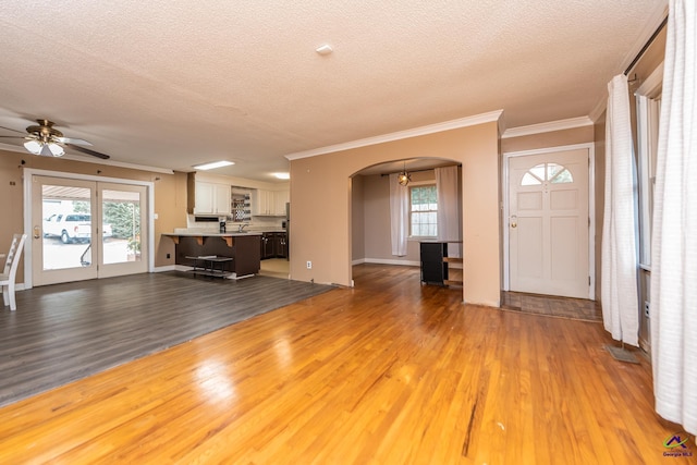 entryway featuring arched walkways, wood finished floors, and a wealth of natural light