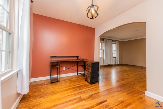 interior space with light wood-type flooring, arched walkways, and baseboards