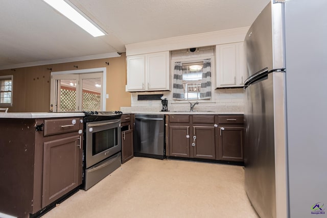 kitchen with stainless steel appliances, a sink, white cabinets, light countertops, and backsplash