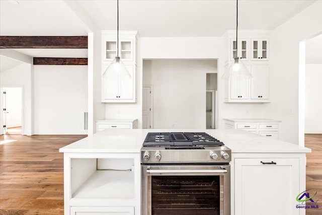 kitchen with wood-type flooring, lofted ceiling with beams, decorative light fixtures, stainless steel range with gas cooktop, and white cabinets