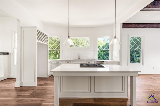 kitchen featuring wood-type flooring, sink, backsplash, a center island, and hanging light fixtures