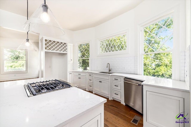 kitchen featuring white cabinetry, stainless steel appliances, sink, backsplash, and pendant lighting