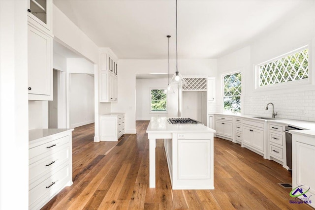 kitchen with white cabinets, pendant lighting, a center island, and hardwood / wood-style floors