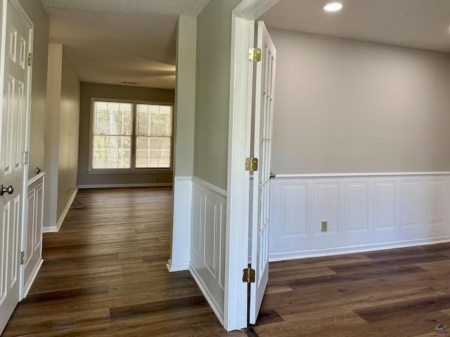 hall with dark hardwood / wood-style flooring and a textured ceiling