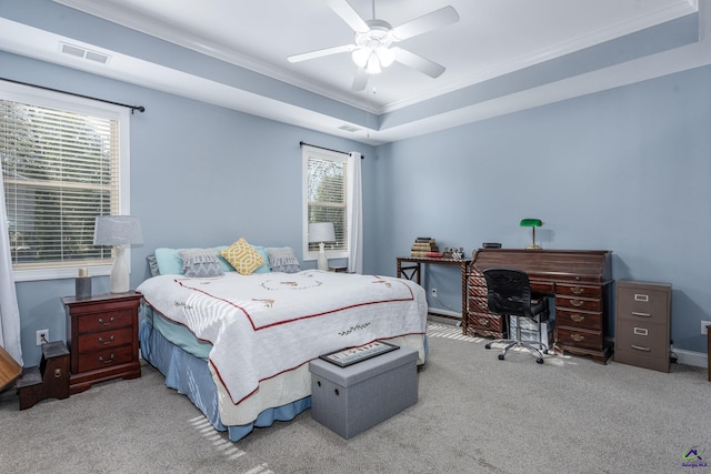 carpeted bedroom with ornamental molding, ceiling fan, and a raised ceiling