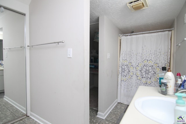 bathroom with a textured ceiling, vanity, and a shower with curtain