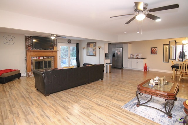 living room featuring a fireplace, ceiling fan, and light wood-type flooring