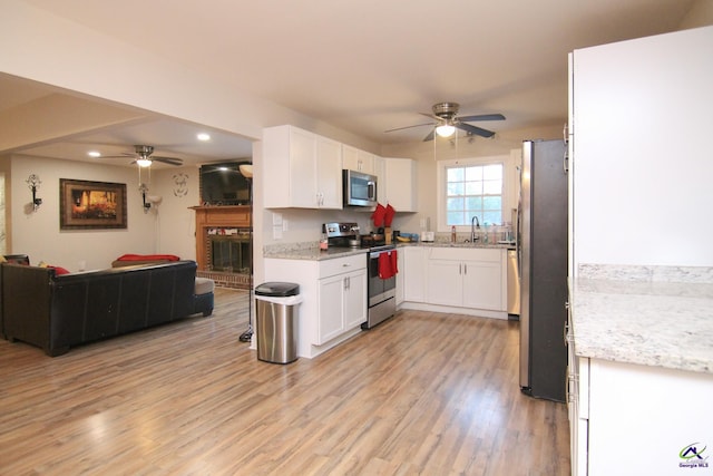 kitchen featuring appliances with stainless steel finishes, light hardwood / wood-style flooring, white cabinets, ceiling fan, and sink