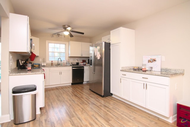 kitchen with stainless steel appliances, sink, ceiling fan, light stone counters, and white cabinets