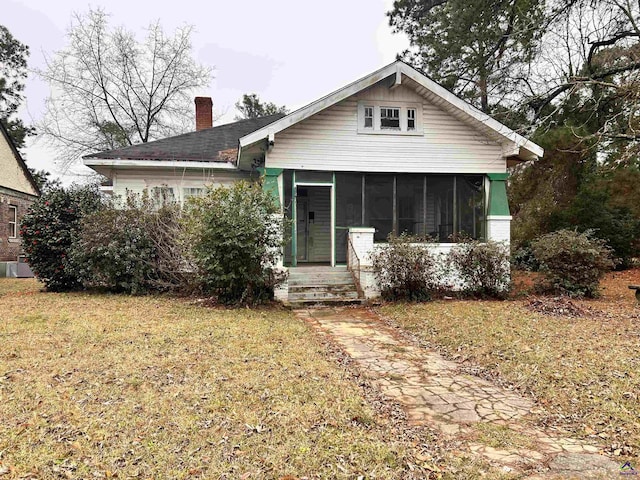 back of property featuring a sunroom and a lawn