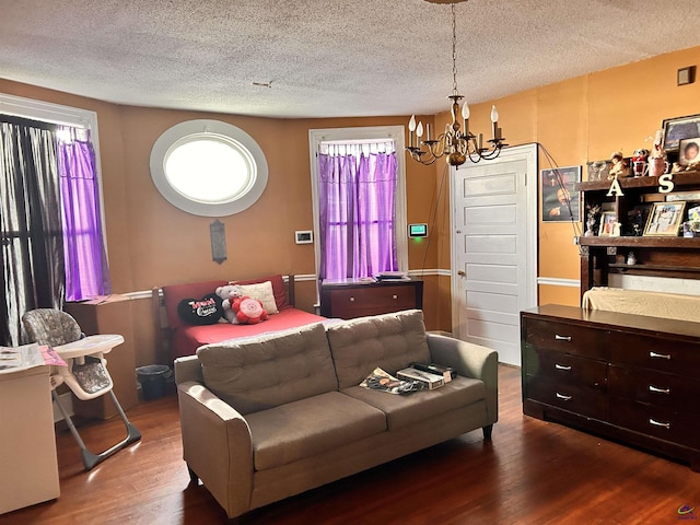 living room featuring a textured ceiling, a notable chandelier, and wood-type flooring