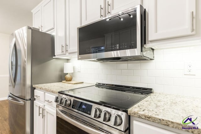 kitchen featuring appliances with stainless steel finishes, white cabinetry, light stone countertops, and tasteful backsplash