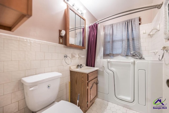 bathroom with tile walls, vanity, tile patterned flooring, and toilet