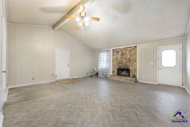 unfurnished living room with parquet floors, a stone fireplace, ceiling fan, lofted ceiling with beams, and a textured ceiling