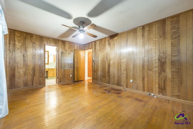 empty room with light hardwood / wood-style flooring and wooden walls