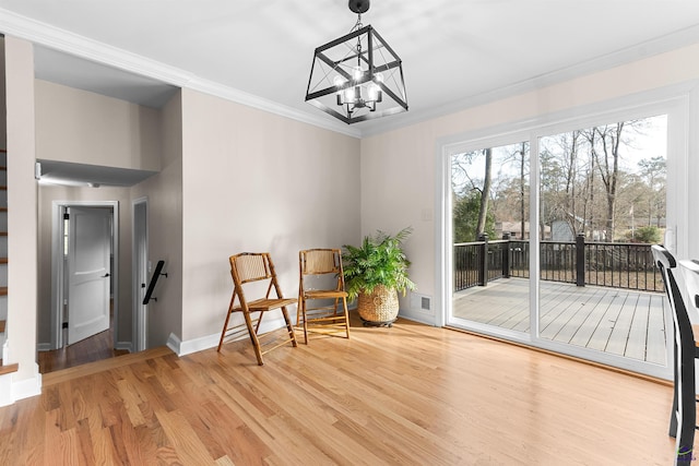 sitting room featuring hardwood / wood-style floors, crown molding, and a chandelier