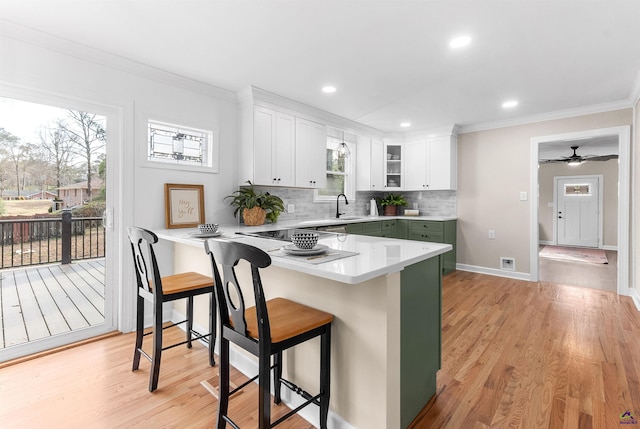 kitchen with a breakfast bar area, kitchen peninsula, white cabinets, and backsplash