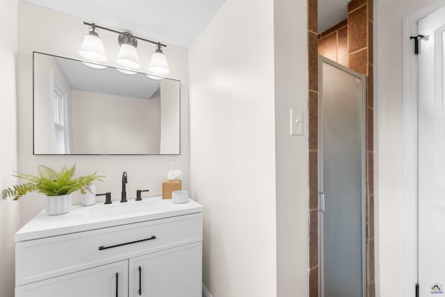 bathroom featuring a shower with shower door and vanity