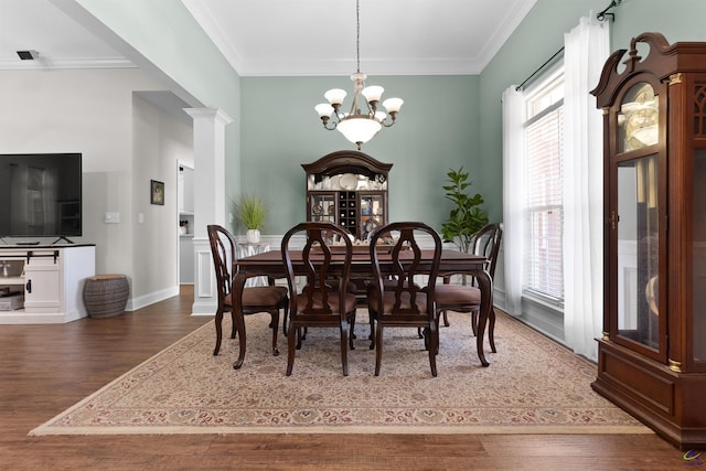 dining space with ornamental molding, dark wood-type flooring, ornate columns, and an inviting chandelier