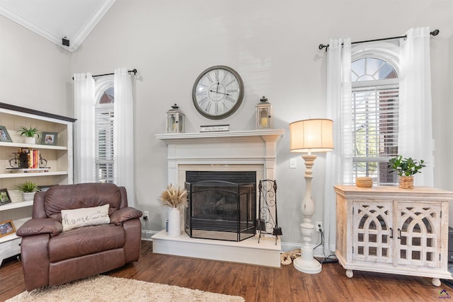 living area featuring hardwood / wood-style flooring, lofted ceiling, and crown molding