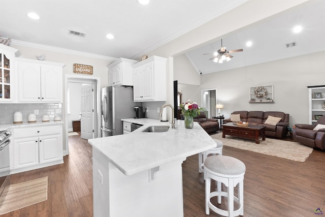 kitchen featuring white cabinetry, kitchen peninsula, stainless steel fridge, sink, and a kitchen breakfast bar