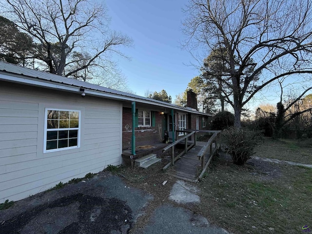 view of front of house featuring brick siding, metal roof, and a chimney