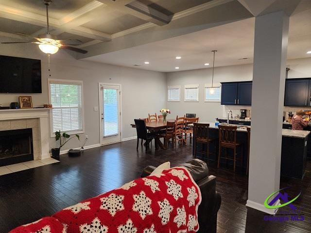 living room with a tile fireplace, coffered ceiling, baseboards, beam ceiling, and dark wood finished floors