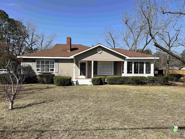 ranch-style home featuring a sunroom, a chimney, and a front yard