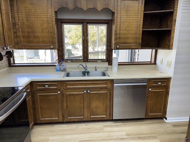 kitchen with stainless steel appliances, light countertops, a sink, and open shelves