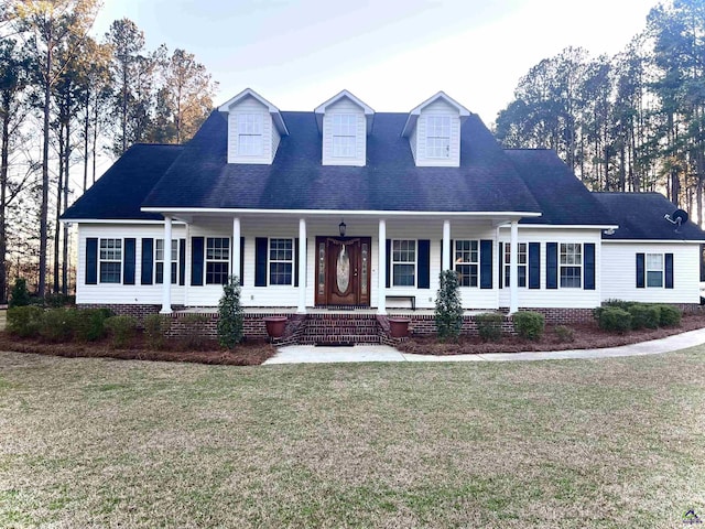 new england style home featuring a shingled roof, a porch, and a front yard